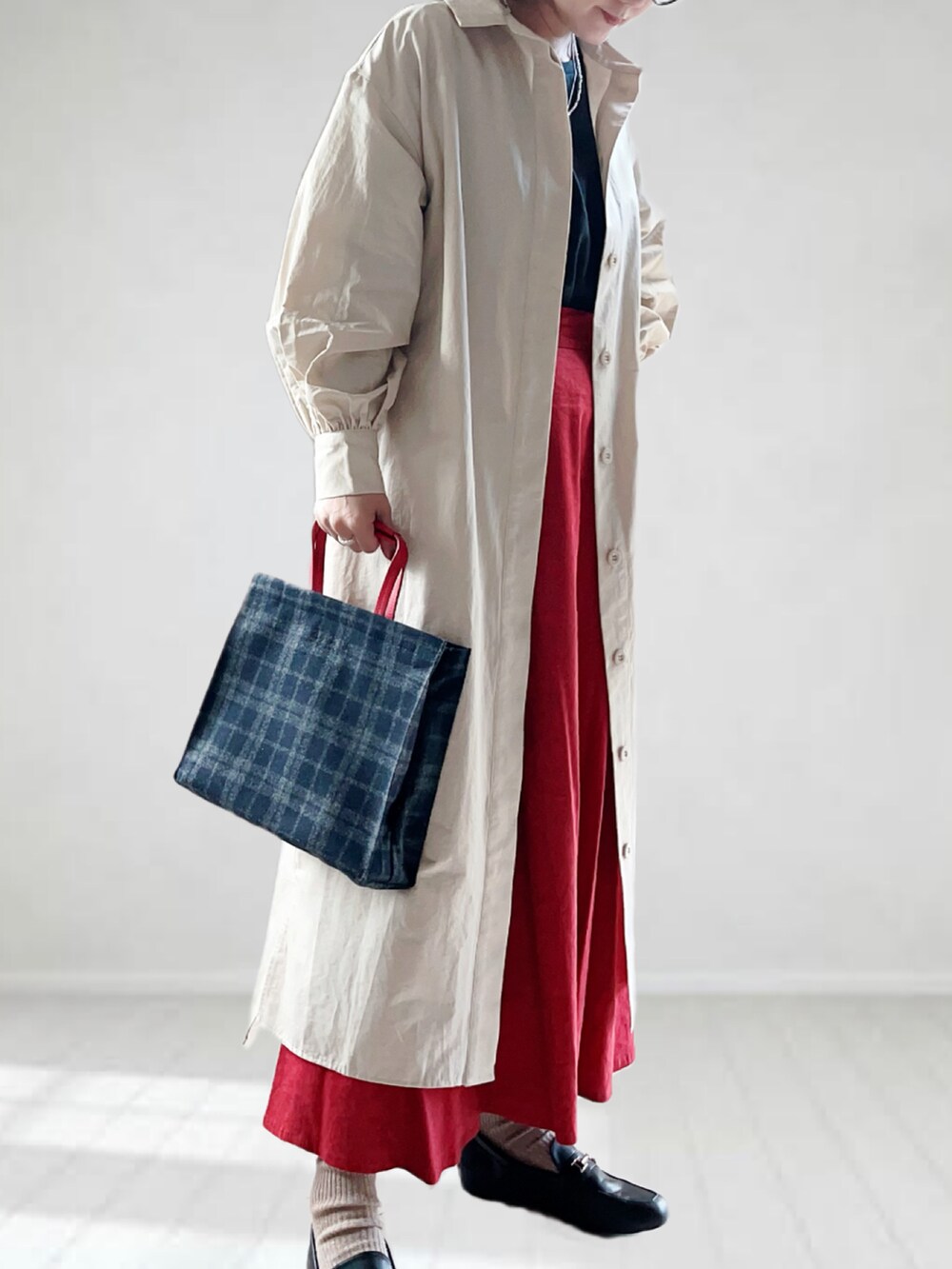 ベージュ系のシャツワンピース、ブルー系のトートバッグ、ブラック系のTシャツ/カットソーを着用したレディースの秋コーディネートの3枚目の写真