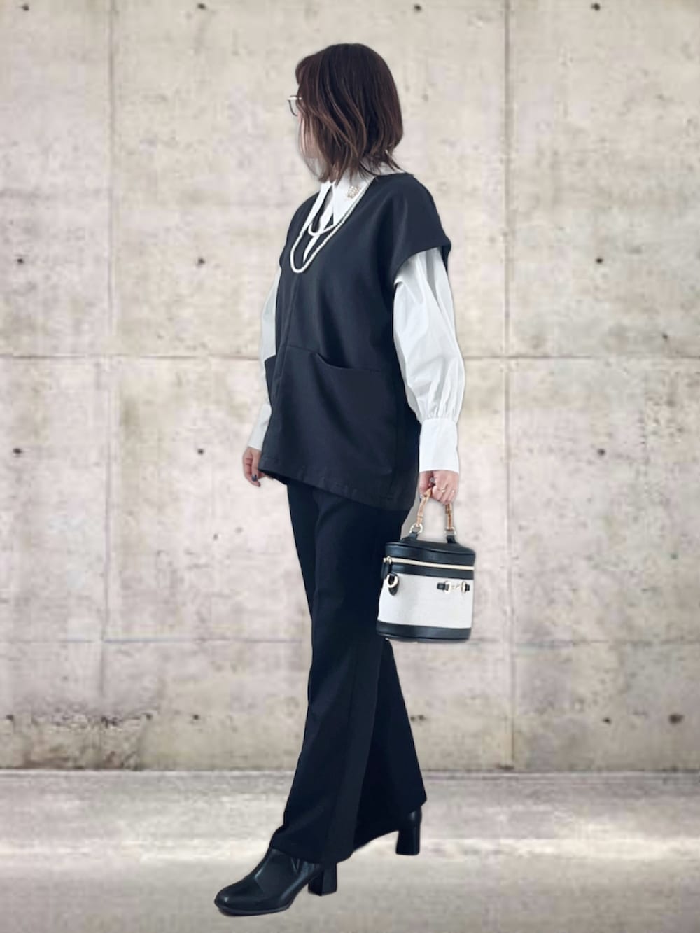 ブラック系のベスト、ホワイト系のシャツ/ブラウス、ブラック系のスラックスを着用したレディースの冬コーディネートの2枚目の写真