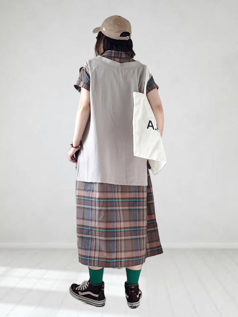 ブラウン系のワンピース、ベージュ系のベスト、ホワイト系のトートバッグを着用したレディースの夏コーディネートの2枚目の写真