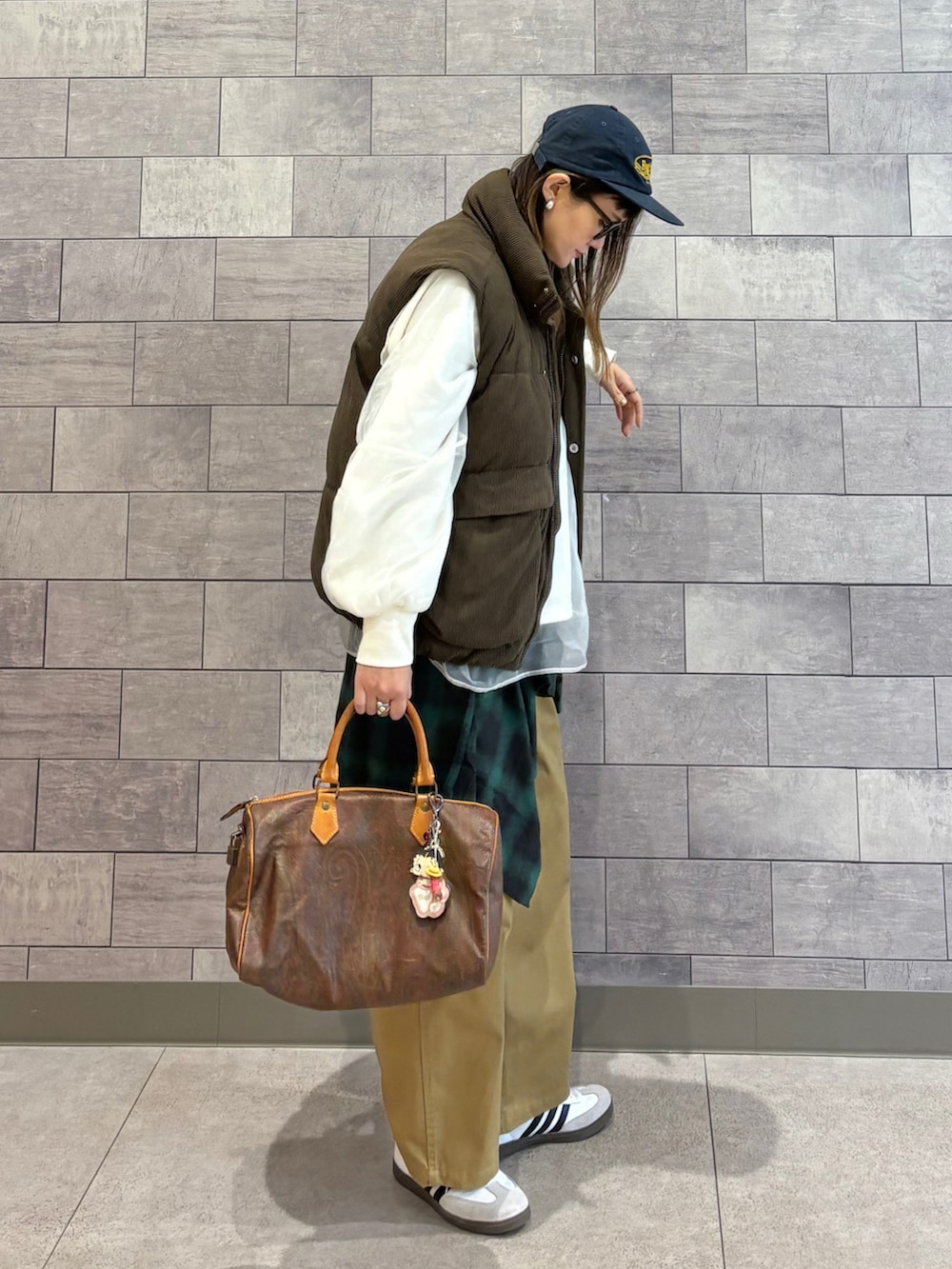 ブラウン系のダウンベスト、ホワイト系のスウェット、グリーン系のシャツ/ブラウスを着用したレディースの冬コーディネートの3枚目の写真