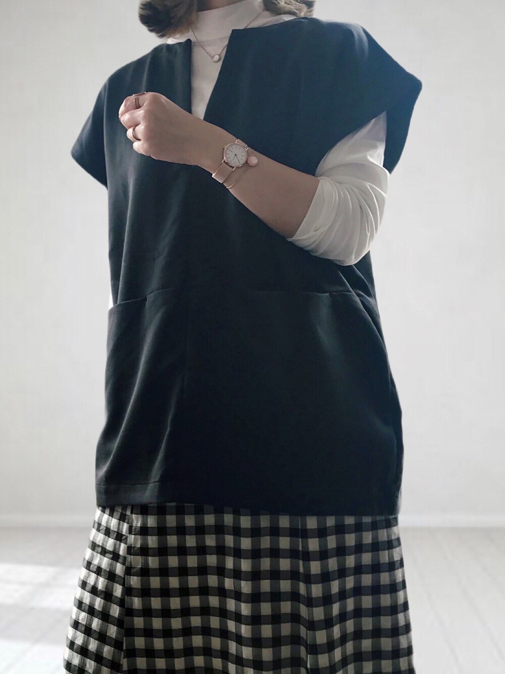 ブラック系のスカート、ホワイト系のTシャツ/カットソー、ブラック系のベストを着用したレディースの春コーディネートの2枚目の写真