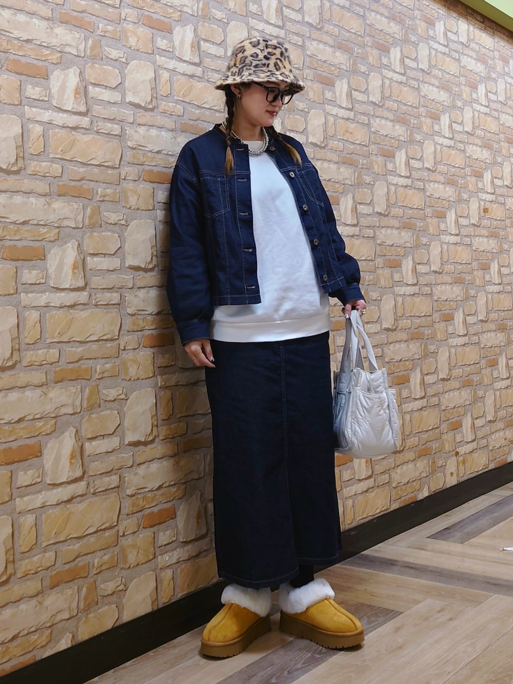 ブルー系のブルゾン、ホワイト系のトートバッグ、イエロー系のブーツを着用したレディースの冬コーディネートの2枚目の写真