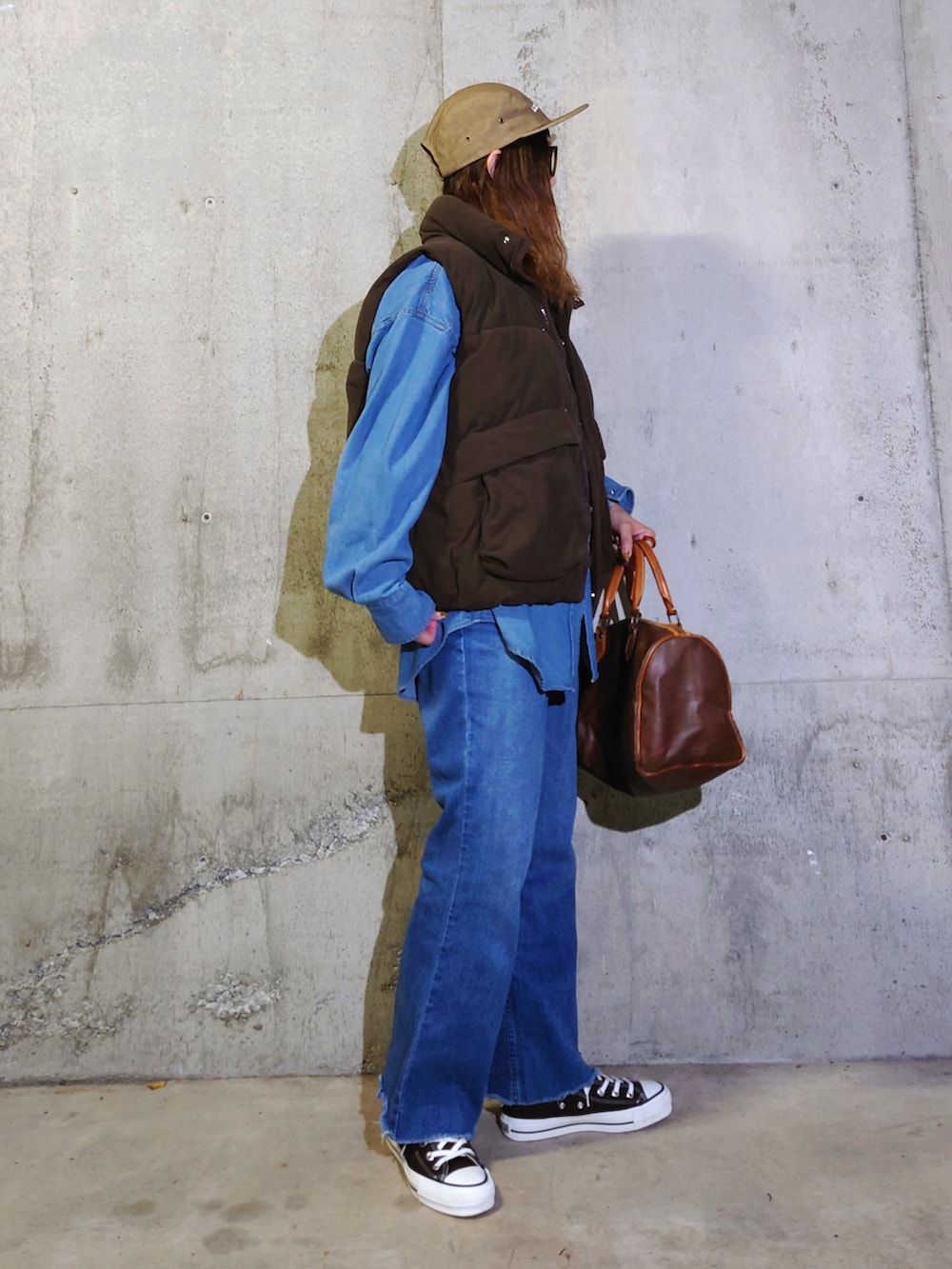 ブラウン系のダウンベスト、ブルー系のシャツ/ブラウス、ブラウン系のスニーカーを着用したレディースの秋コーディネートの2枚目の写真