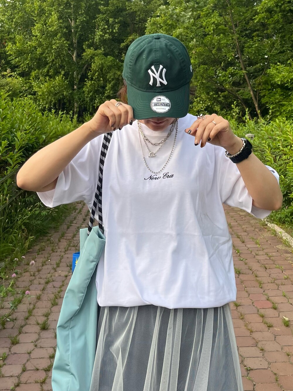 ホワイト系のTシャツ/カットソー、ブルー系のデニムパンツ、ホワイト系のスカートを着用したレディースの夏コーディネートの5枚目の写真