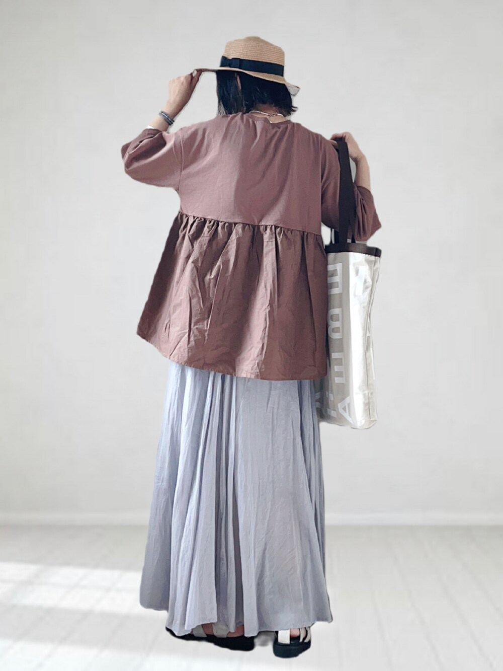 ブラウン系のTシャツ/カットソー、グレー系のスカート、グレー系のトートバッグを着用したレディースの夏コーディネートの2枚目の写真