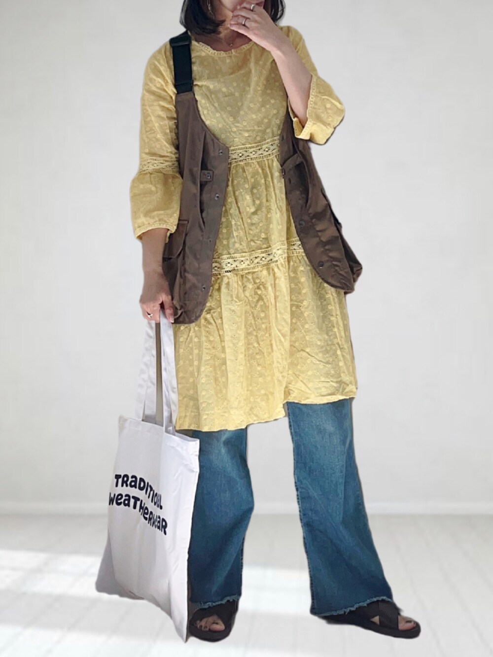 ブルー系のデニムパンツ、ホワイト系のトートバッグ、ブラウン系のサンダルを着用したレディースの夏コーディネートの2枚目の写真