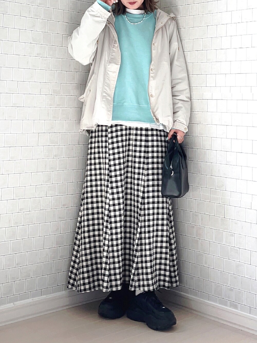 ホワイト系のマウンテンパーカー、ブルー系のTシャツ/カットソー、ブラック系のスカートを着用したレディースの春コーディネートの4枚目の写真