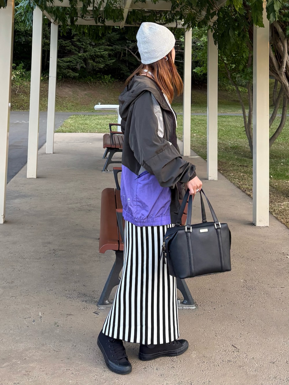 ブラック系のマウンテンパーカー、ホワイト系のスカート、ブラック系のスニーカーを着用したレディースの秋コーディネートの4枚目の写真