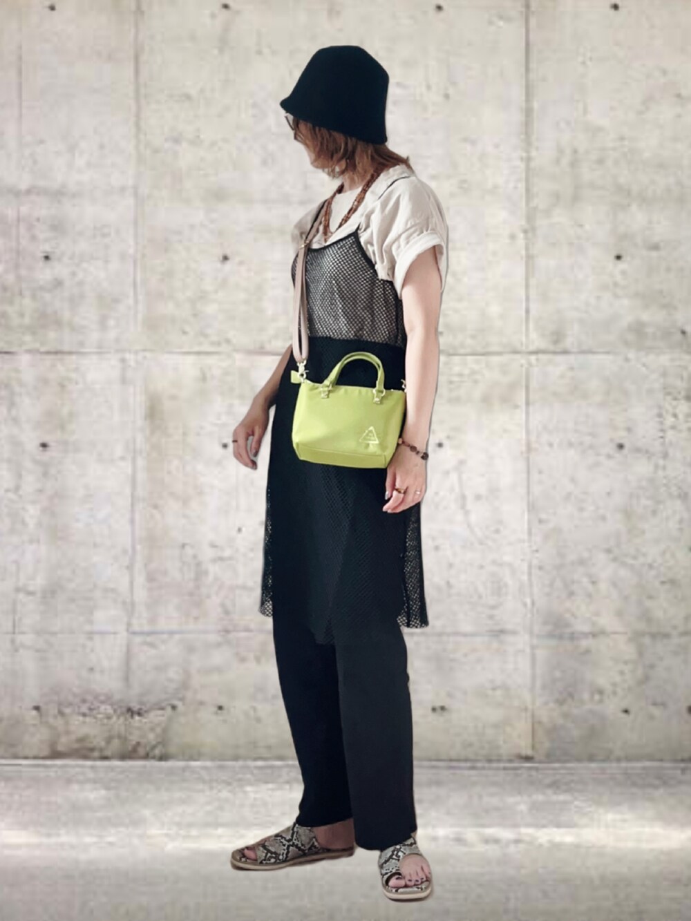 グリーン系のショルダーバッグ、ブラック系のワンピース、ベージュ系のTシャツ/カットソーを着用したレディースの夏コーディネートの2枚目の写真