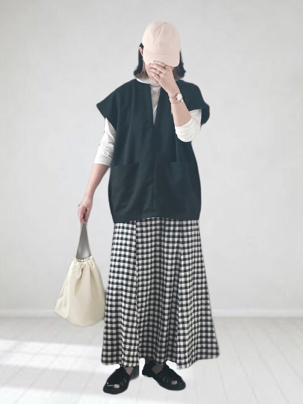 ブラック系のスカート、ホワイト系のTシャツ/カットソー、ブラック系のベストを着用したレディースの春コーディネートの4枚目の写真