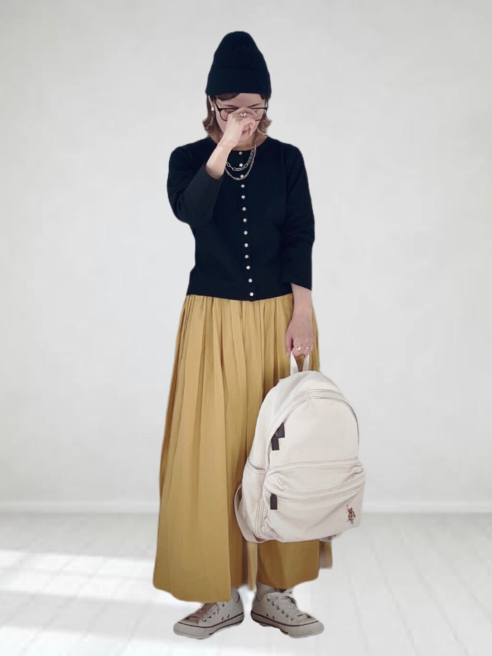 ブラック系のカーディガン/ボレロ、イエロー系のスカート、ホワイト系のバックパック/リュックを着用したレディースの春コーディネートの3枚目の写真