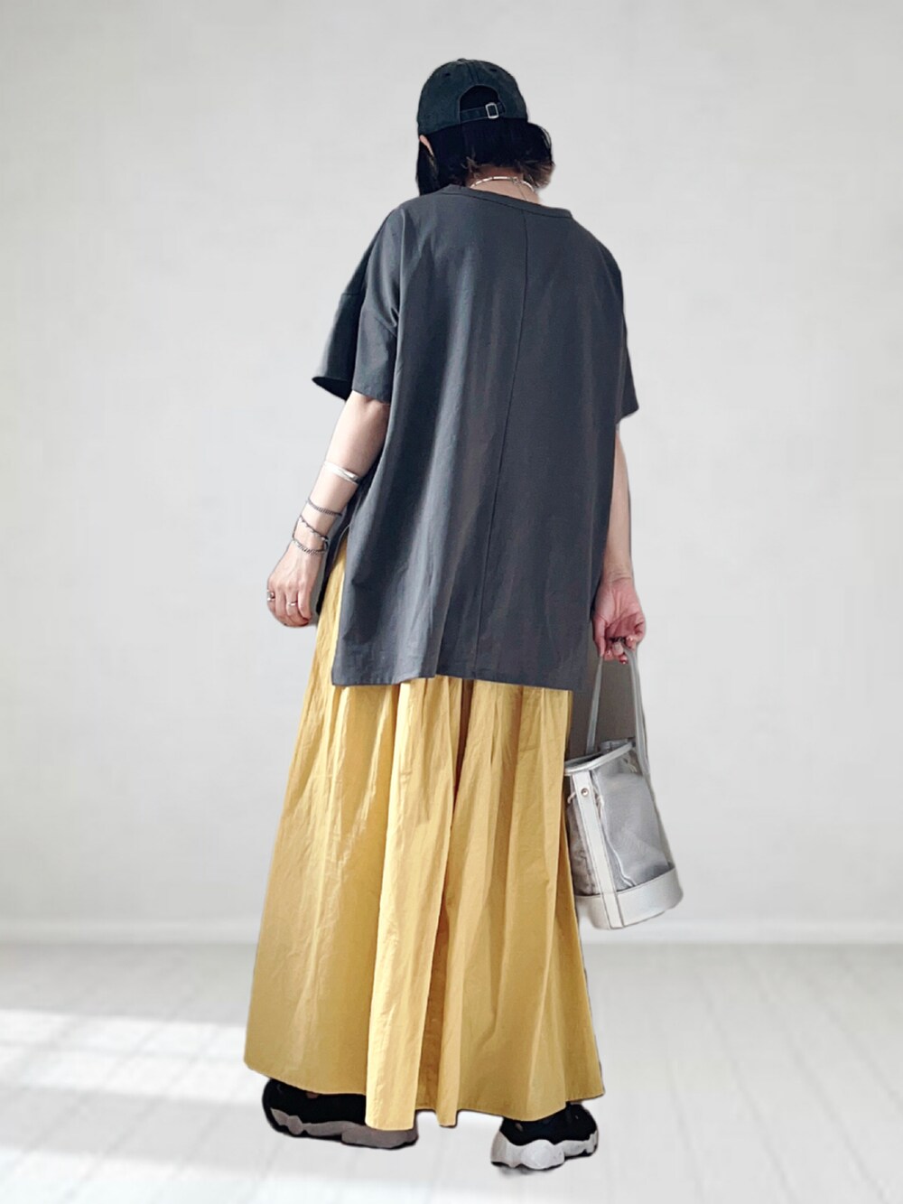 グレー系のTシャツ/カットソー、イエロー系のスカート、シルバー系のショルダーバッグを着用したレディースの夏コーディネートの3枚目の写真