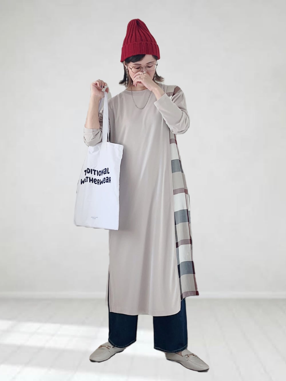 ベージュ系のワンピース、ブルー系のデニムパンツ、ホワイト系のトートバッグを着用したレディースの秋コーディネートの2枚目の写真