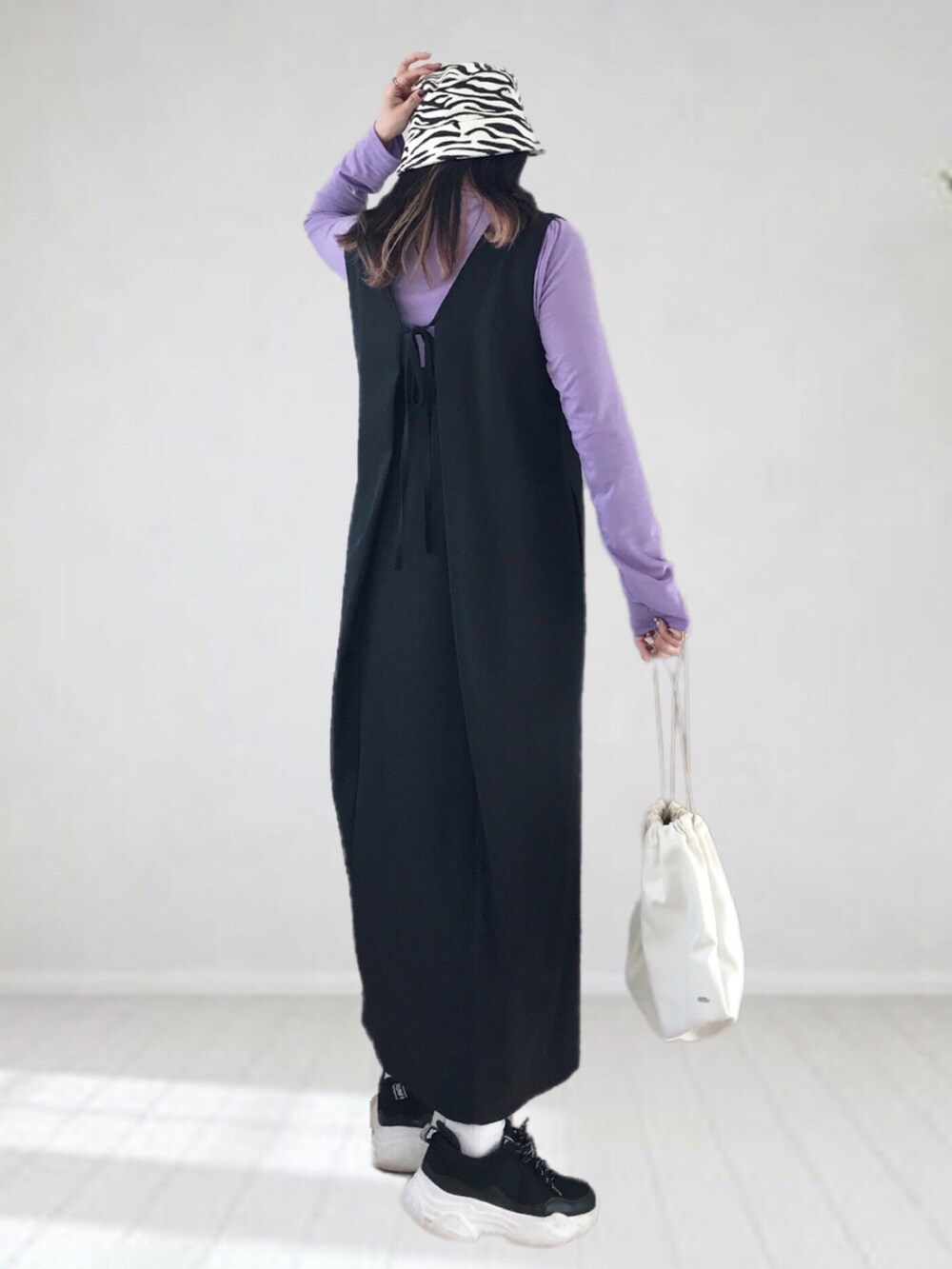 ブラック系のジャンパースカート、パープル系のTシャツ/カットソー、ホワイト系のショルダーバッグを着用したレディースの冬コーディネートの3枚目の写真