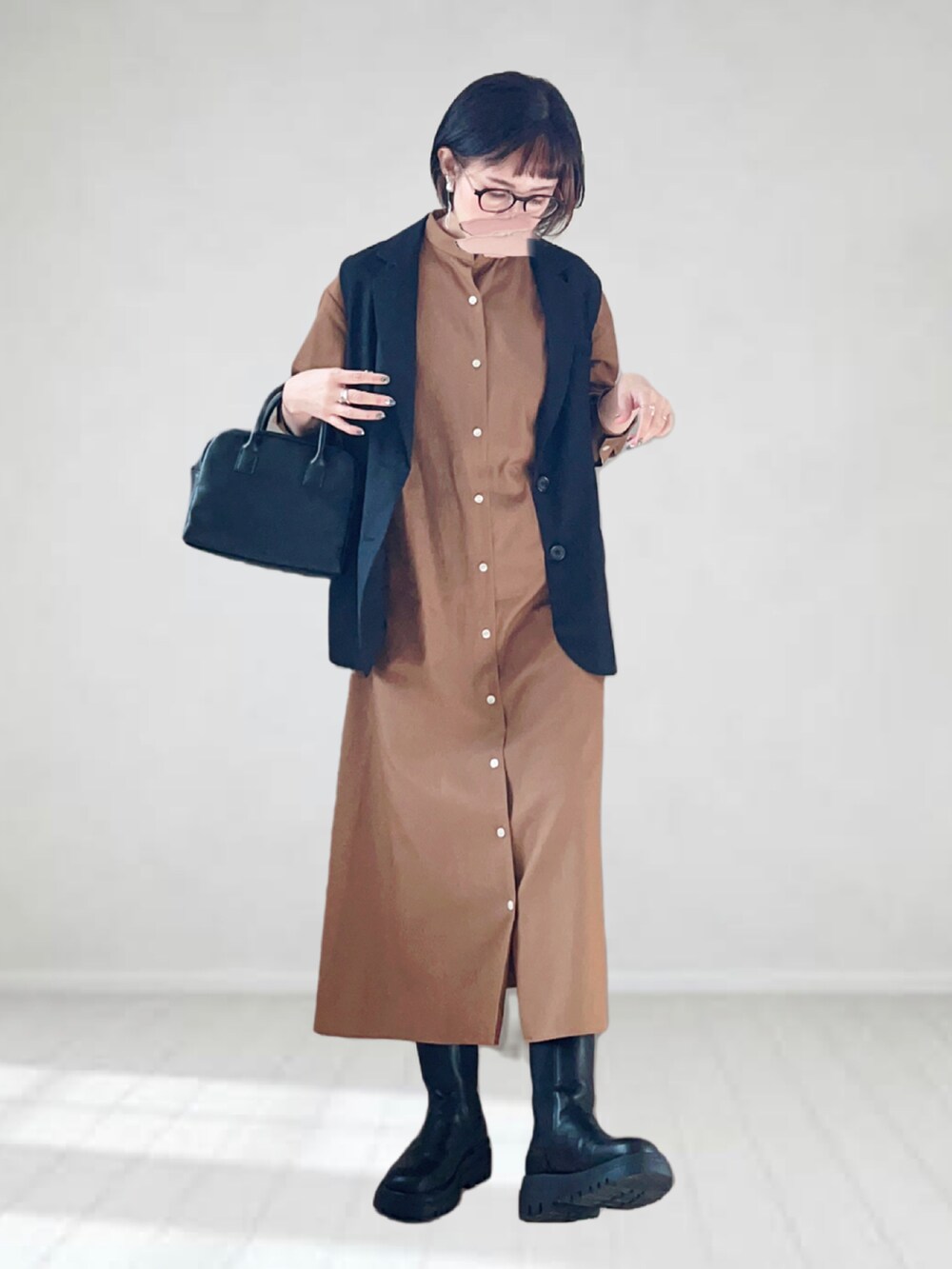 ベージュ系のワンピース、ブラック系のベスト、ブラック系のボストンバッグを着用したレディースの秋コーディネートの2枚目の写真