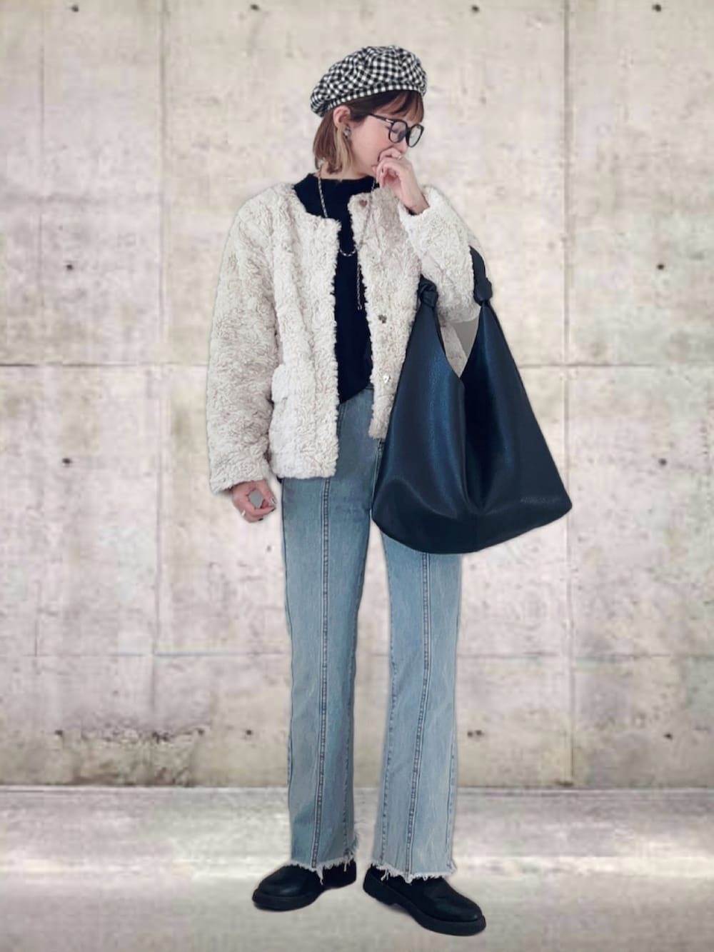 ベージュ系のノーカラーコート、ブルー系のデニムパンツ、ブラック系のトートバッグを着用したレディースの冬コーディネートの2枚目の写真