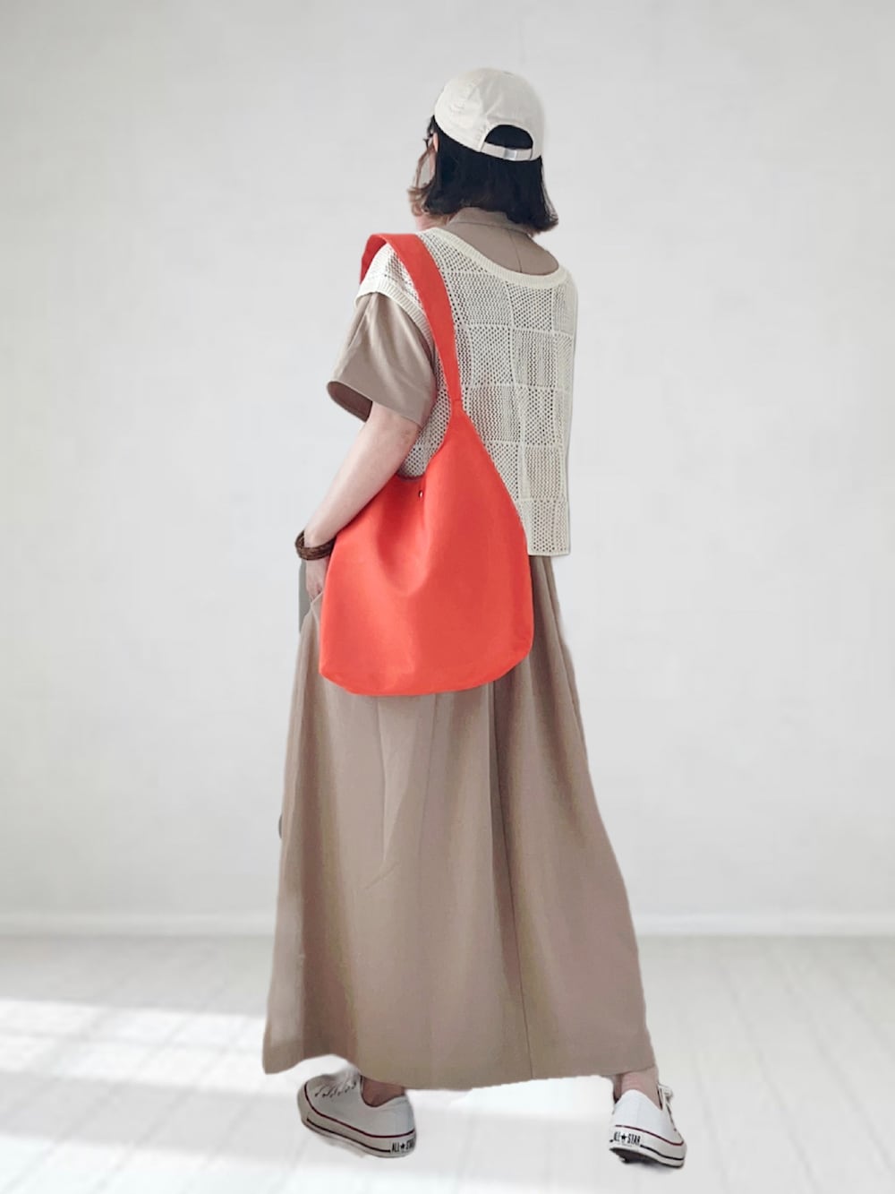 ベージュ系のワンピース、ホワイト系のニット/セーター、オレンジ系のトートバッグを着用したレディースの夏コーディネートの2枚目の写真