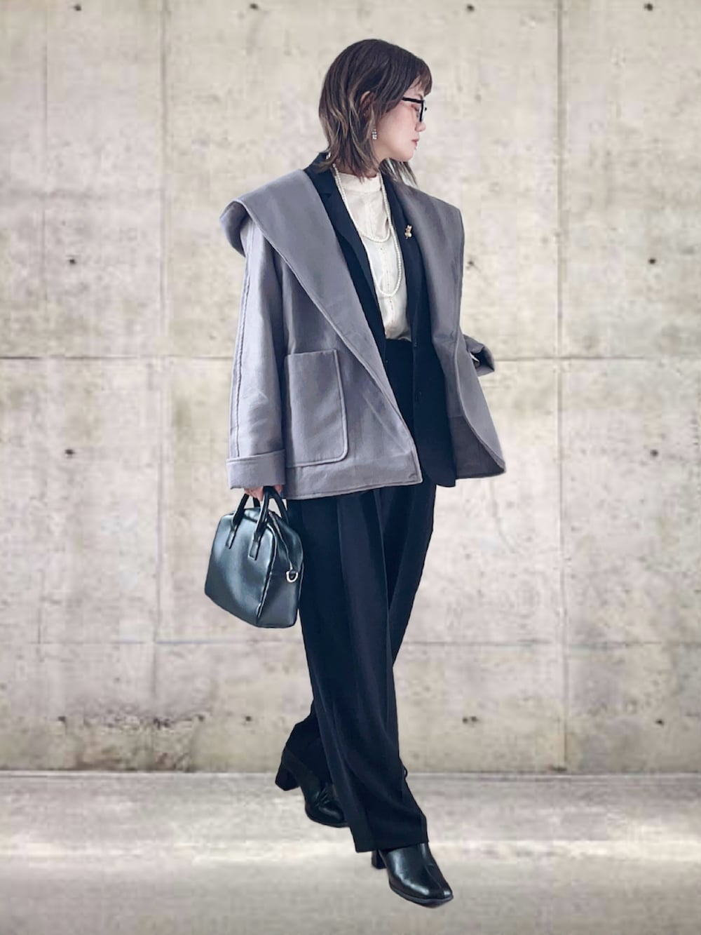 グレー系のポンチョ、ブラック系のベスト、ホワイト系のシャツ/ブラウスを着用したレディースの冬コーディネートの3枚目の写真