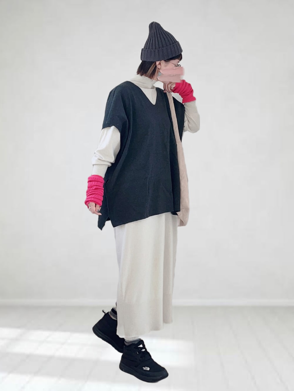 ホワイト系のワンピース、グレー系のベスト、ホワイト系のトートバッグを着用したレディースの冬コーディネートの2枚目の写真