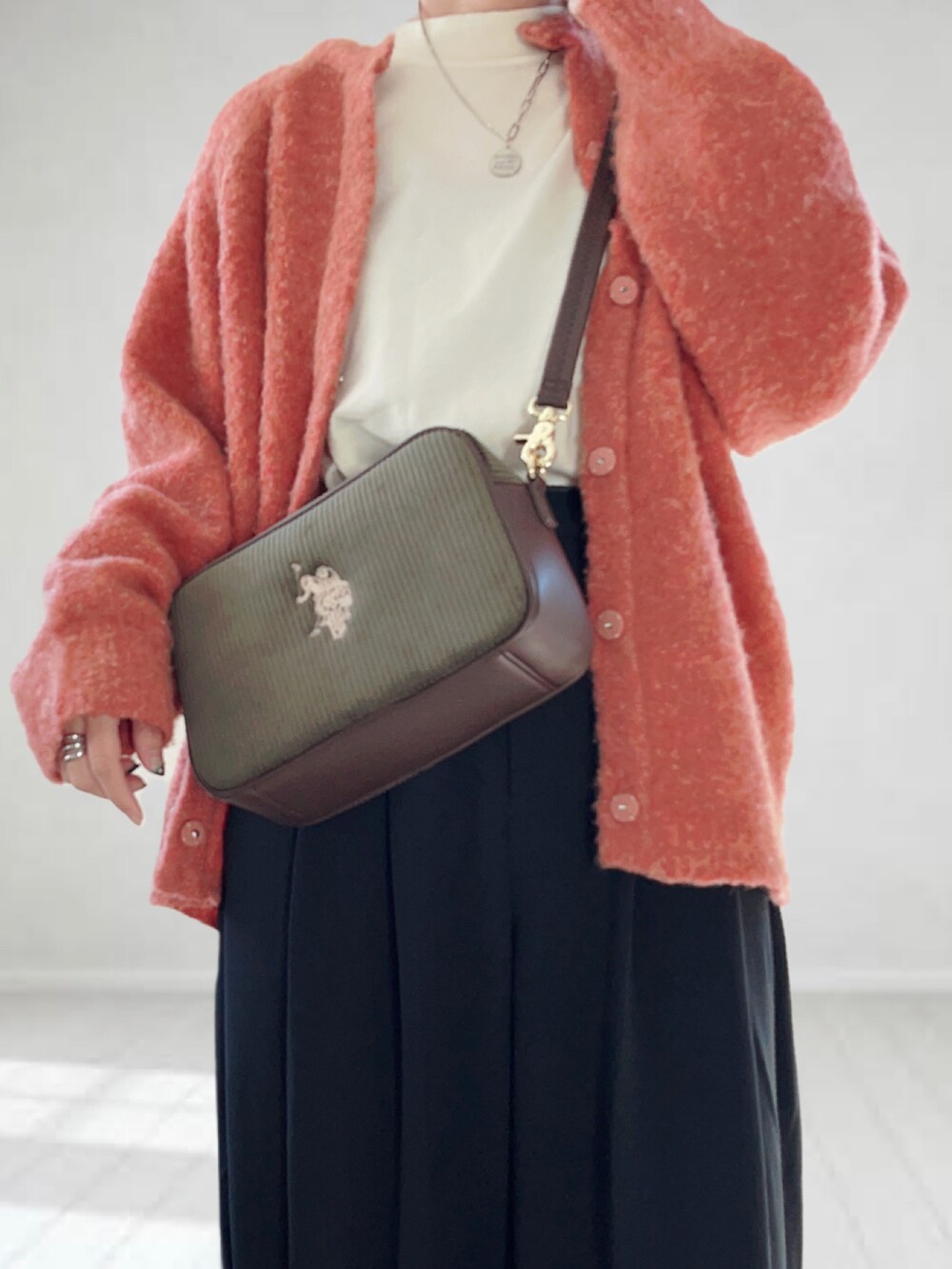 グリーン系のショルダーバッグ、ピンク系のカーディガン/ボレロ、ホワイト系のニット/セーターを着用したレディースの冬コーディネートの3枚目の写真
