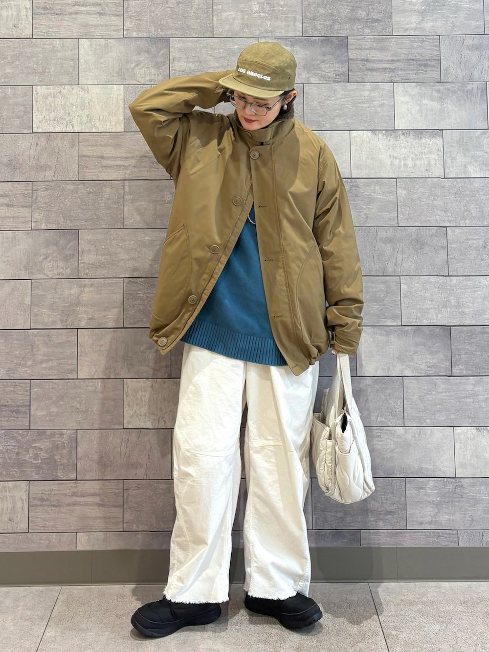 ベージュ系のミリタリージャケット、ブルー系のニット/セーター、ホワイト系のその他パンツを着用したレディースの冬コーディネートの5枚目の写真