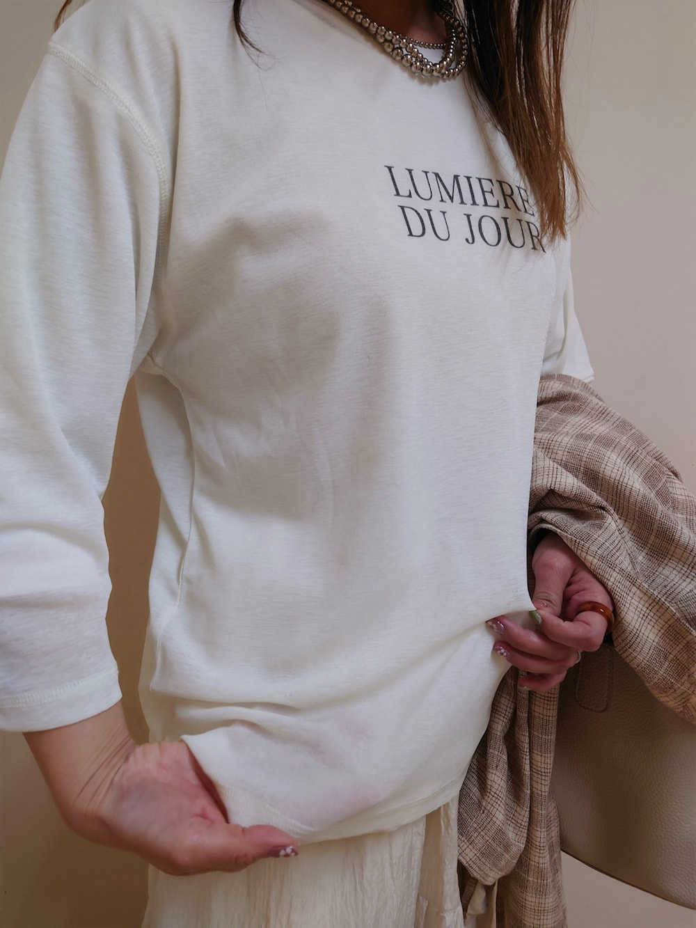 ホワイト系のアンサンブル、ブラウン系のスニーカー、ベージュ系のテーラードジャケットを着用したレディースの春コーディネートの4枚目の写真