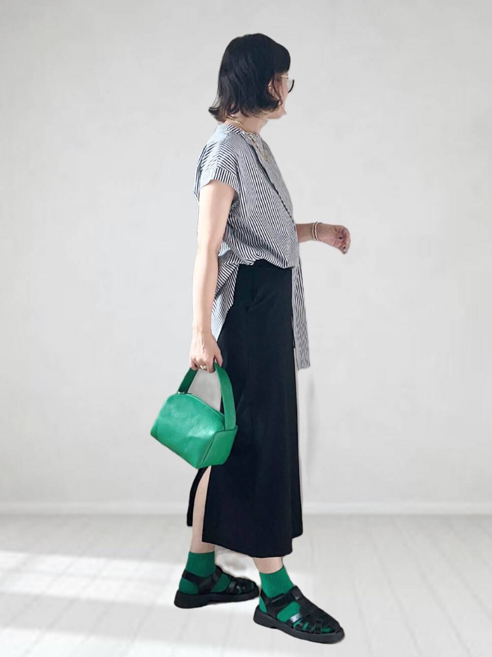 ブラック系のシャツ/ブラウス、ブラック系のスカート、グリーン系のショルダーバッグを着用したレディースの夏コーディネートの2枚目の写真
