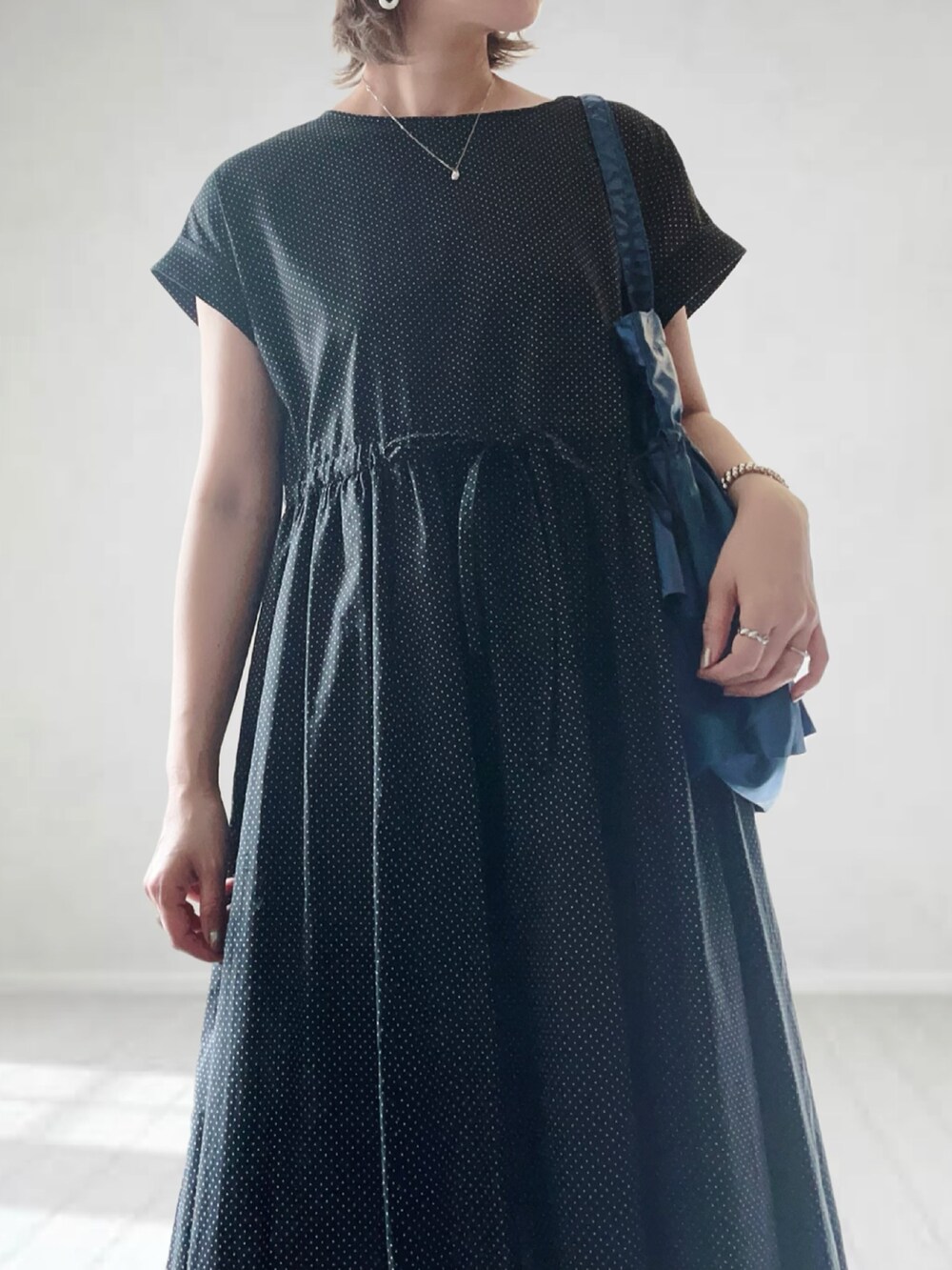 ブラック系のワンピース、ブルー系のバッグ、ブラック系のサンダルを着用したレディースの夏コーディネートの3枚目の写真