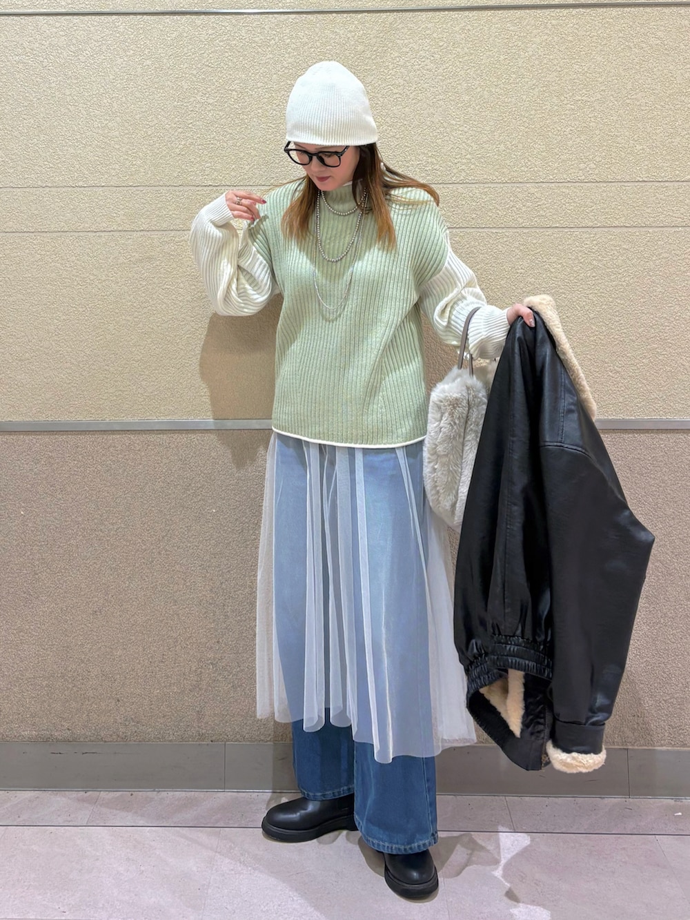 グリーン系のニット/セーター、ホワイト系のスカート、ブルー系のデニムパンツを着用したレディースの冬コーディネートの4枚目の写真