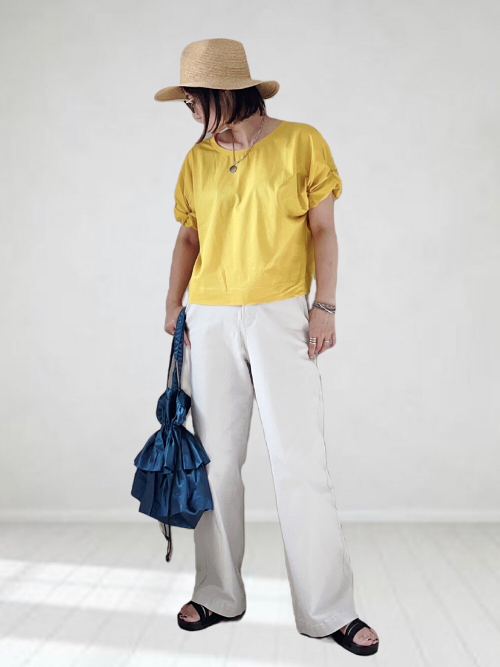 イエロー系のTシャツ/カットソー、グレー系のパンツ、ブルー系のバッグを着用したレディースの夏コーディネートの4枚目の写真