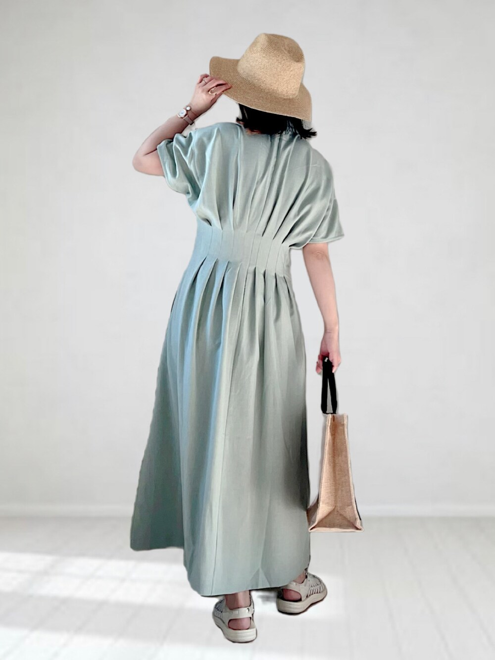 グリーン系のワンピース、ブラック系のかごバッグ、ホワイト系のサンダルを着用したレディースの春コーディネートの2枚目の写真