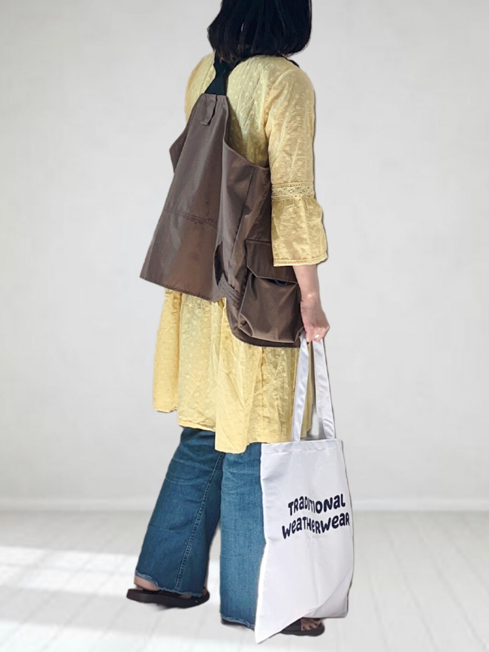 ブルー系のデニムパンツ、ホワイト系のトートバッグ、ブラウン系のサンダルを着用したレディースの夏コーディネートの3枚目の写真