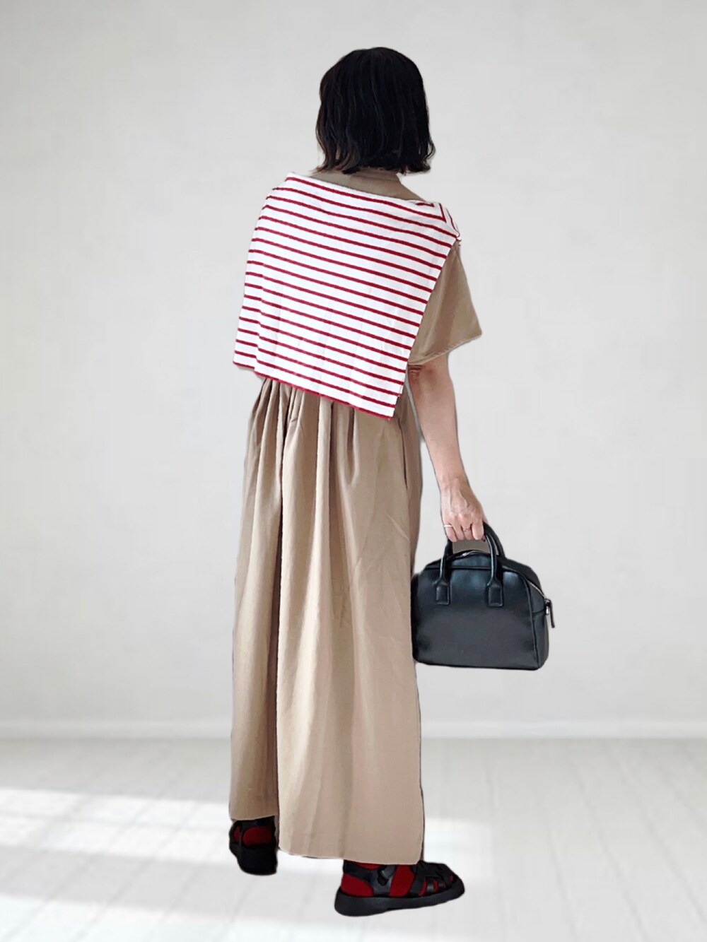 ベージュ系のワンピース、ホワイト系のTシャツ/カットソー、ブラック系のボストンバッグを着用したレディースの夏コーディネートの2枚目の写真