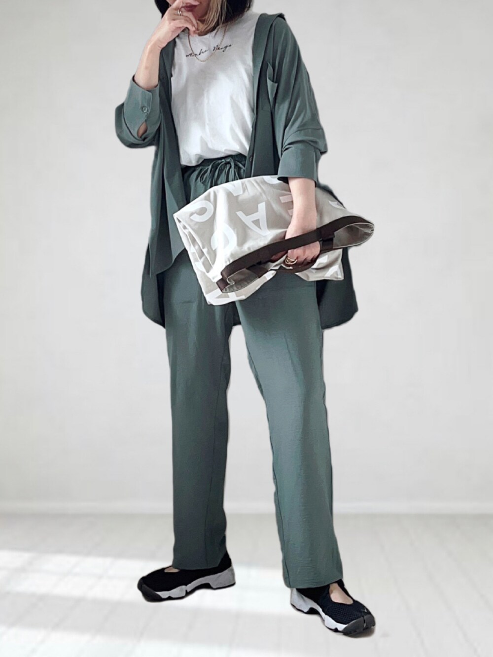 グレー系のトートバッグ、グリーン系のシャツ/ブラウス、ホワイト系のTシャツ/カットソーを着用したレディースの夏コーディネートの2枚目の写真