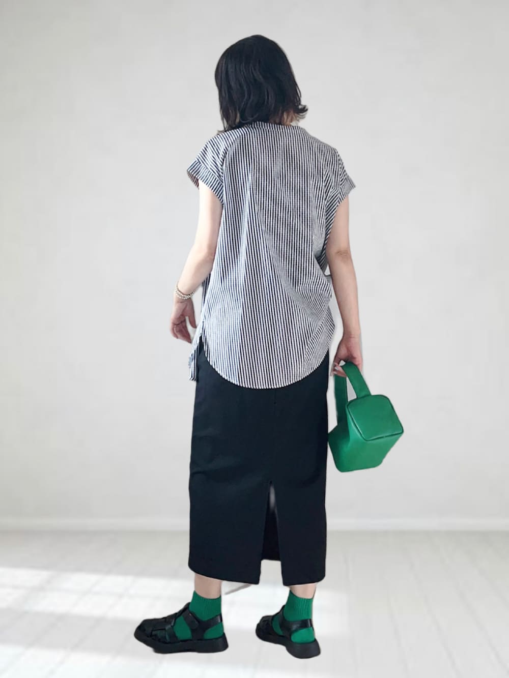 ブラック系のシャツ/ブラウス、ブラック系のスカート、グリーン系のショルダーバッグを着用したレディースの夏コーディネートの3枚目の写真