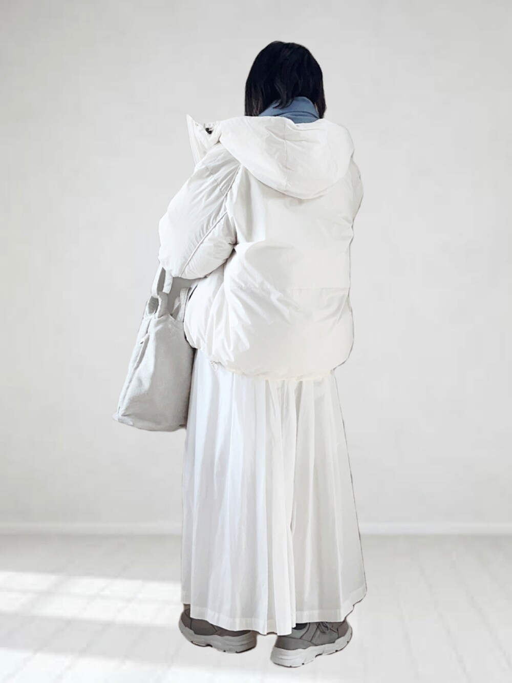 グレー系のTシャツ/カットソー、ホワイト系のダウンジャケット/コート、グレー系のスニーカーを着用したレディースの秋コーディネートの2枚目の写真