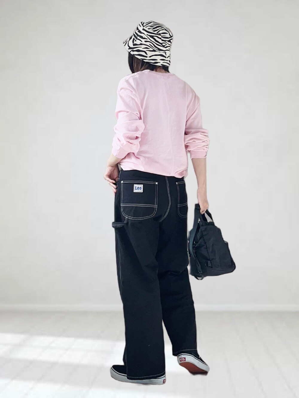 ブラック系のデニムパンツ、ピンク系のTシャツ/カットソー、ブラック系のショルダーバッグを着用したレディースの秋コーディネートの2枚目の写真