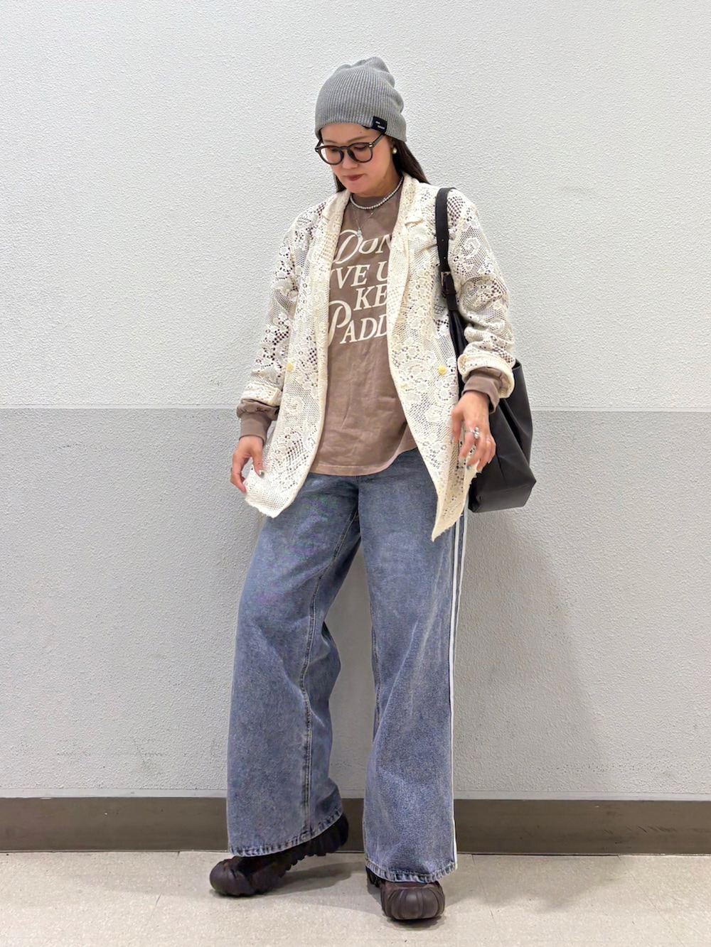 ブラウン系のショルダーバッグ、ブルー系のデニムパンツ、ブラウン系のスニーカーを着用したレディースの夏コーディネートの2枚目の写真
