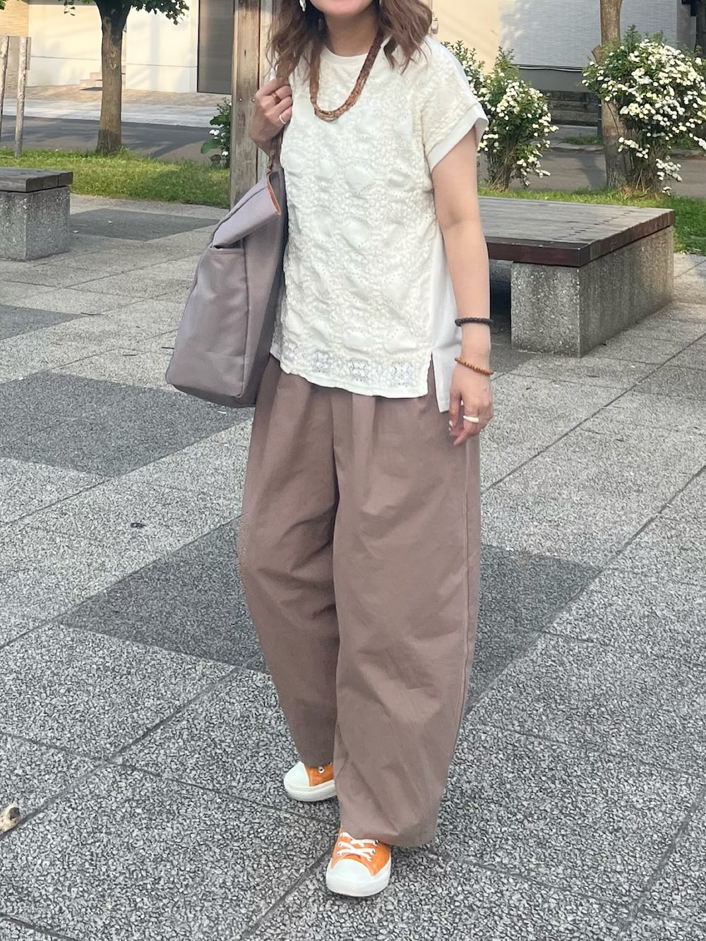 グレー系のトートバッグ、ホワイト系のTシャツ/カットソー、オレンジ系のスニーカーを着用したレディースの夏コーディネートの5枚目の写真