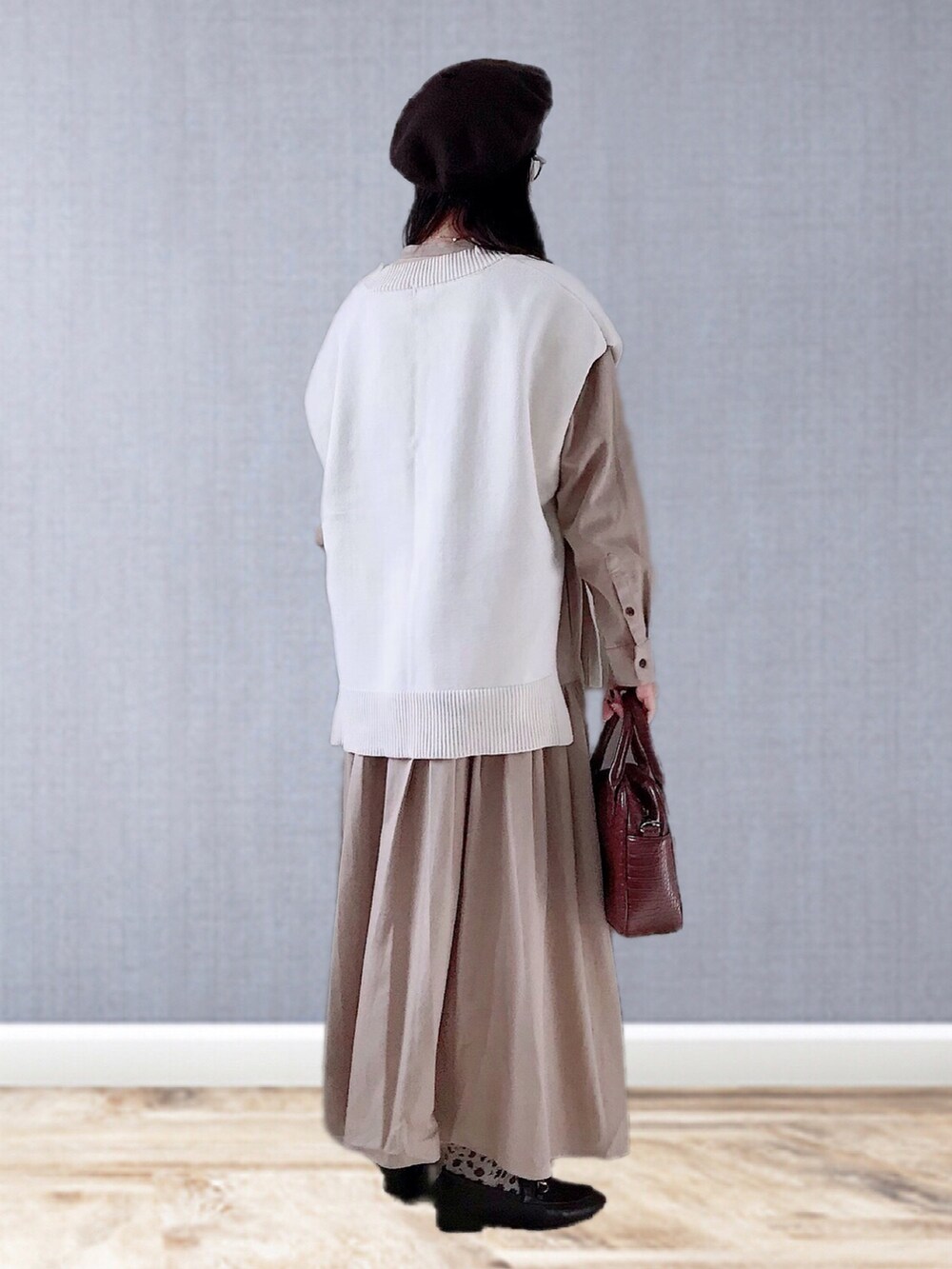 ベージュ系のワンピース、ホワイト系のベスト、ブラウン系のハンドバッグを着用したレディースの冬コーディネートの3枚目の写真