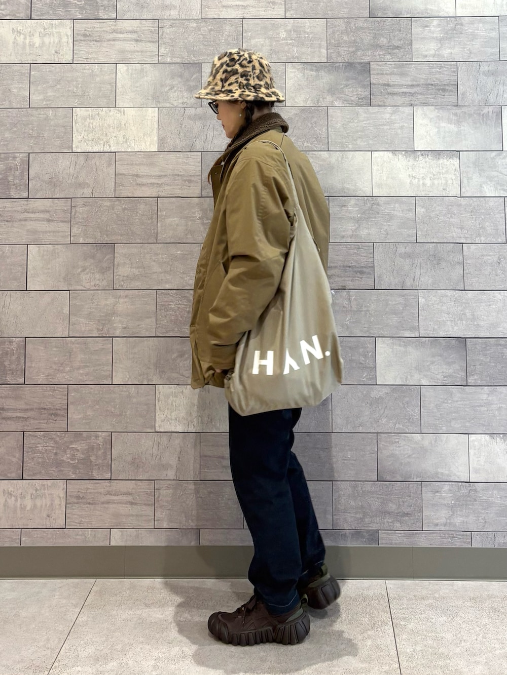 ベージュ系のミリタリージャケット、ホワイト系のスウェット、ブルー系のその他パンツを着用したレディースの春コーディネートの3枚目の写真