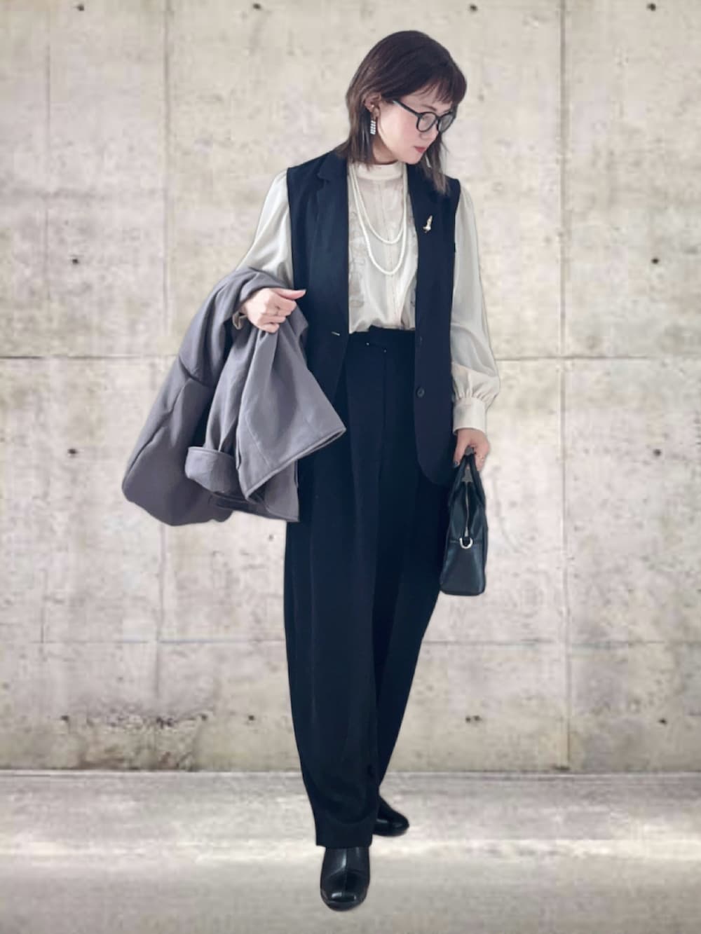 グレー系のポンチョ、ブラック系のベスト、ホワイト系のシャツ/ブラウスを着用したレディースの冬コーディネートの2枚目の写真