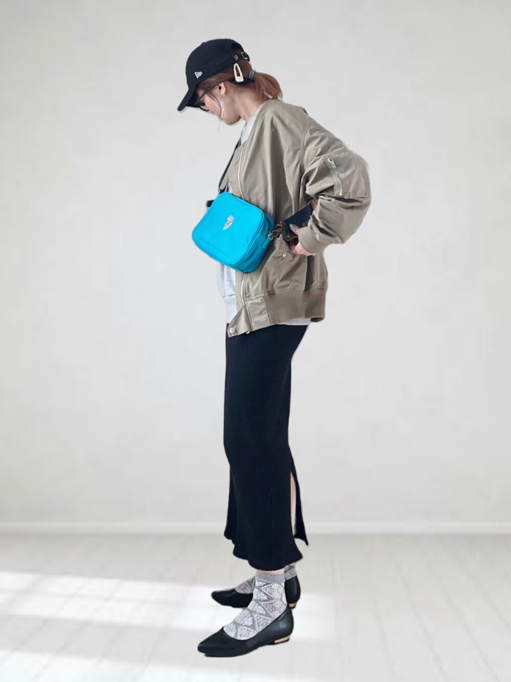 ブルー系のショルダーバッグ、ブラック系のパンプス、グリーン系のMA-1を着用したレディースの春コーディネートの3枚目の写真