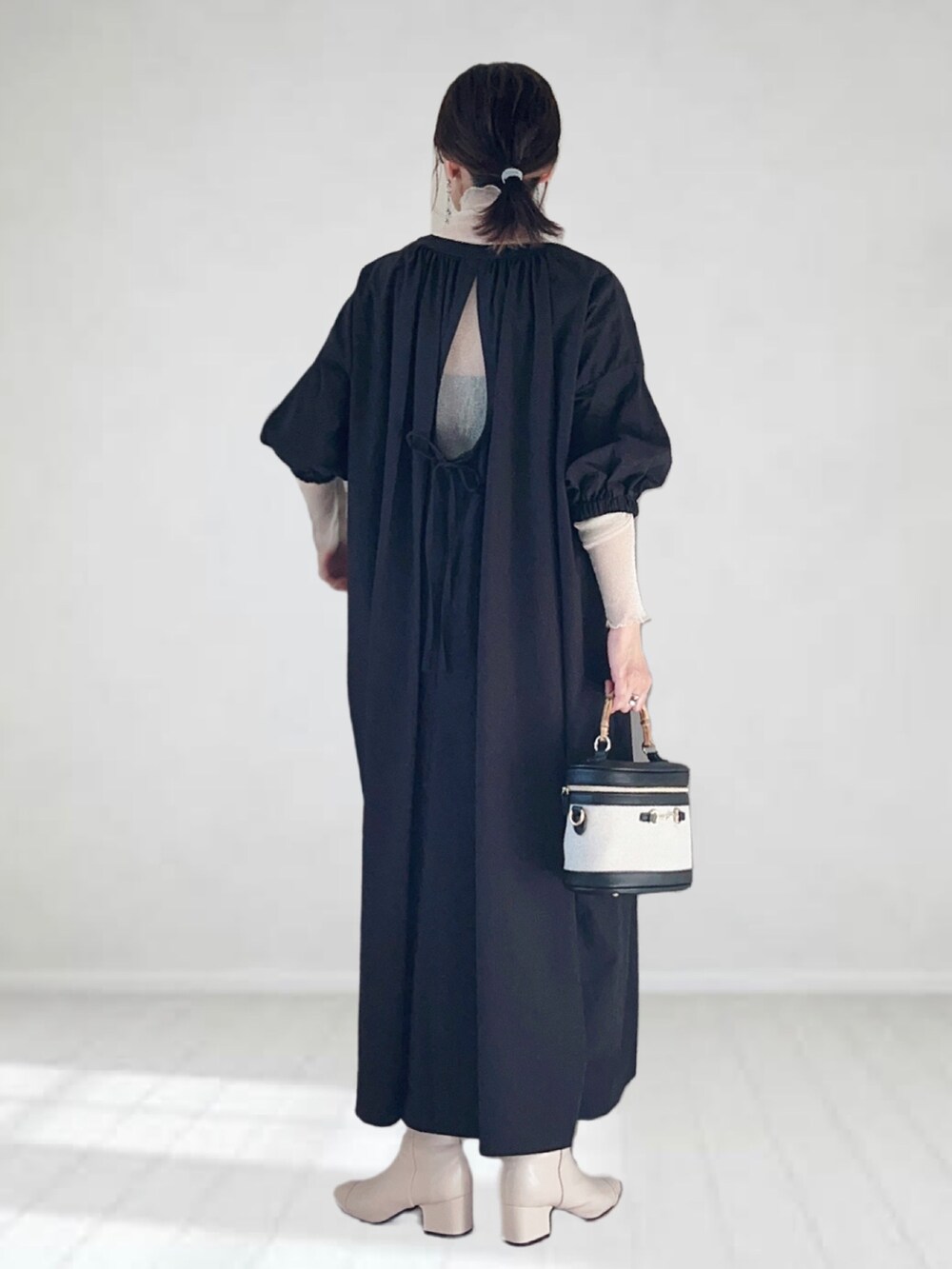 ブラック系のワンピース、ホワイト系のTシャツ/カットソー、ホワイト系のハンドバッグを着用したレディースの秋コーディネートの2枚目の写真