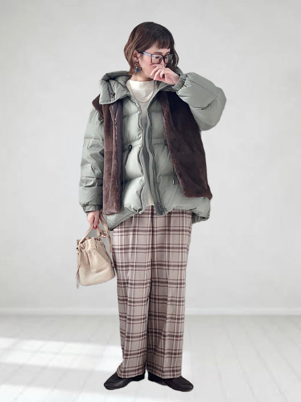 グリーン系のダウンジャケット/コート、ブラウン系のベスト、ホワイト系のニット/セーターを着用したレディースの冬コーディネートの3枚目の写真