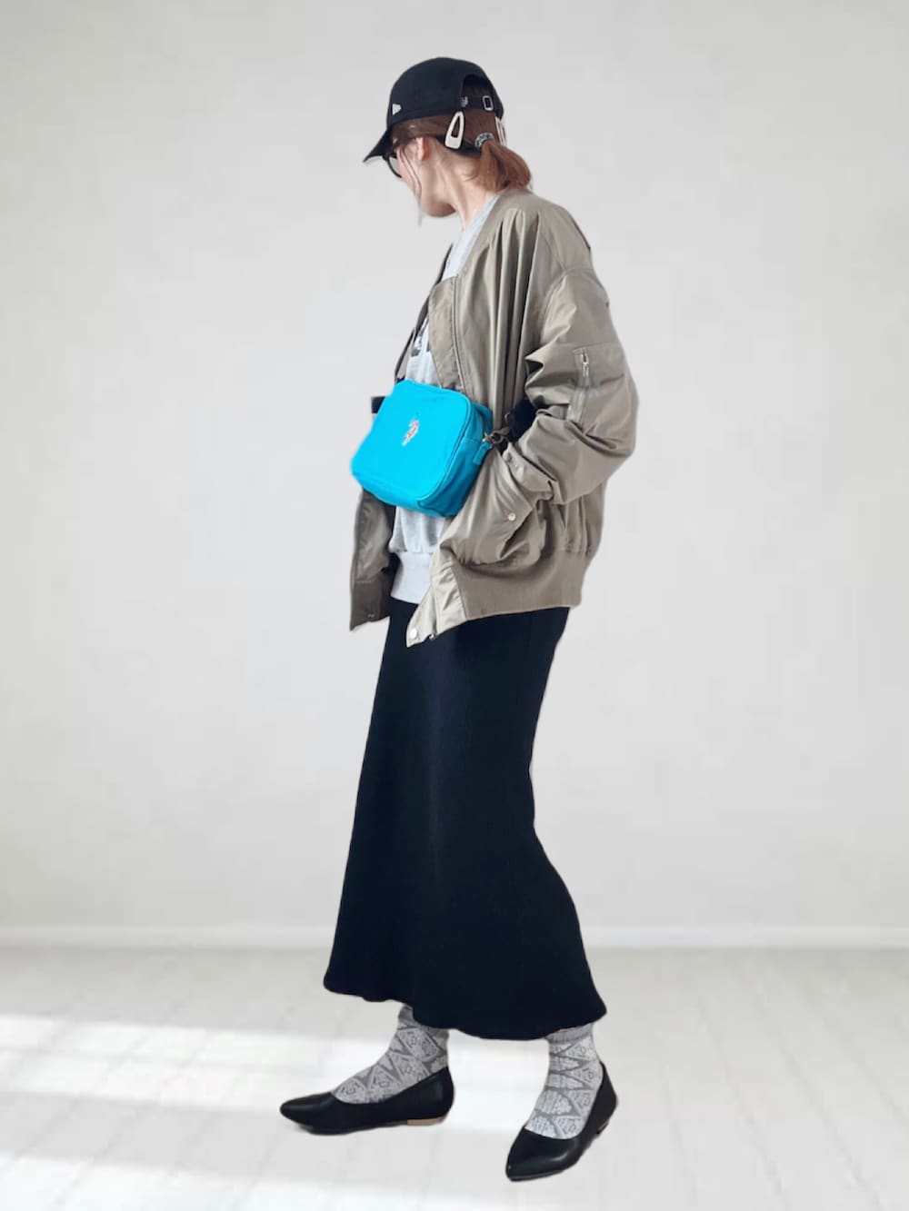 ブルー系のショルダーバッグ、ブラック系のパンプス、グリーン系のMA-1を着用したレディースの春コーディネートの2枚目の写真