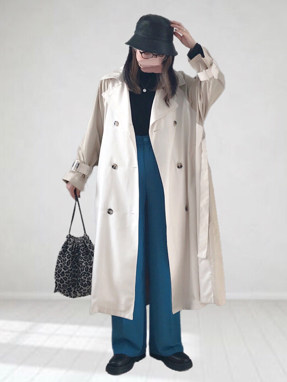 ベージュ系のトレンチコート、ブラック系のニット/セーター、ブルー系のスラックスを着用したレディースの冬コーディネートの3枚目の写真