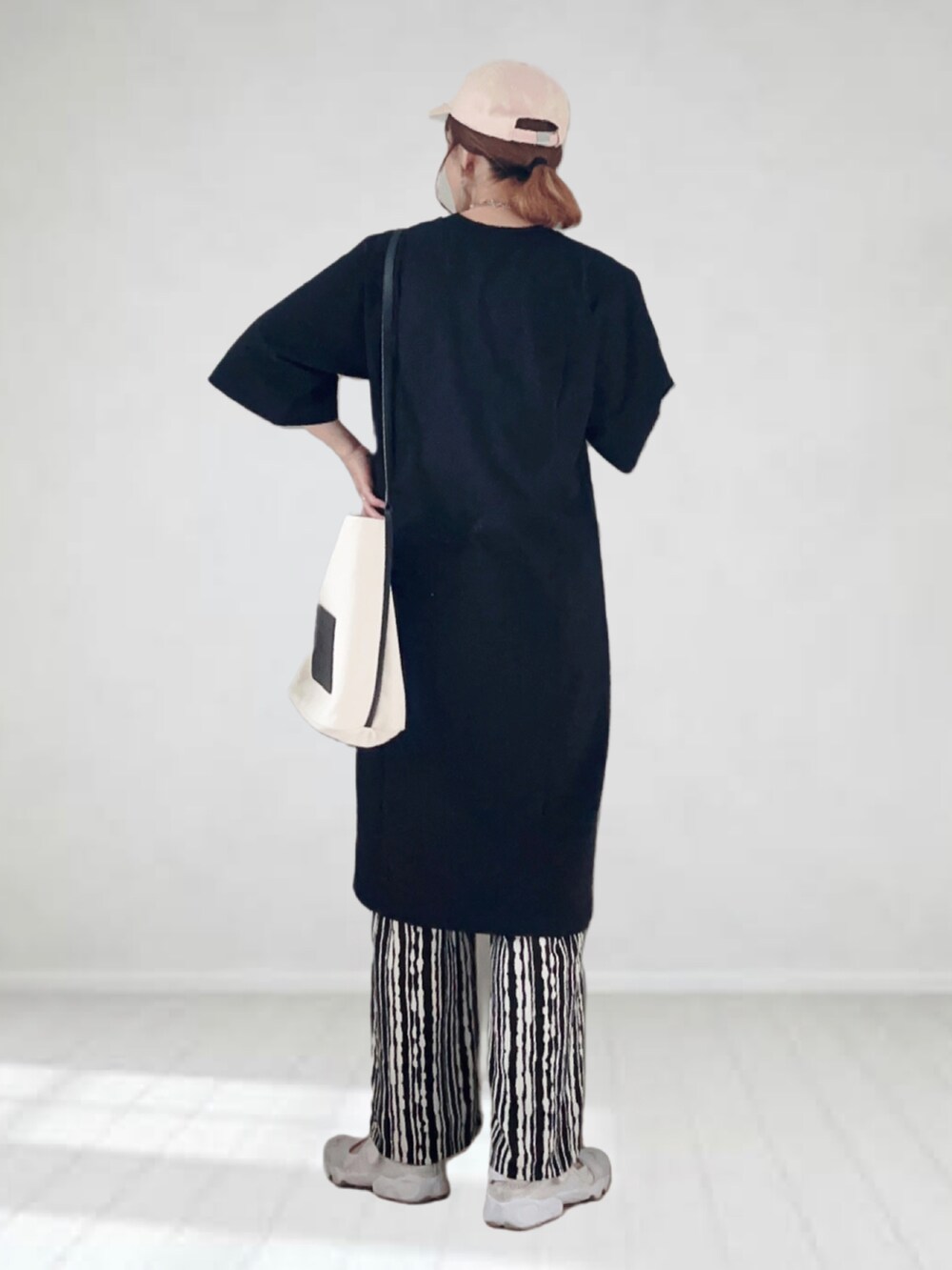 ブラック系のワンピース、ブラック系のその他パンツ、ホワイト系のショルダーバッグを着用したレディースの春コーディネートの2枚目の写真