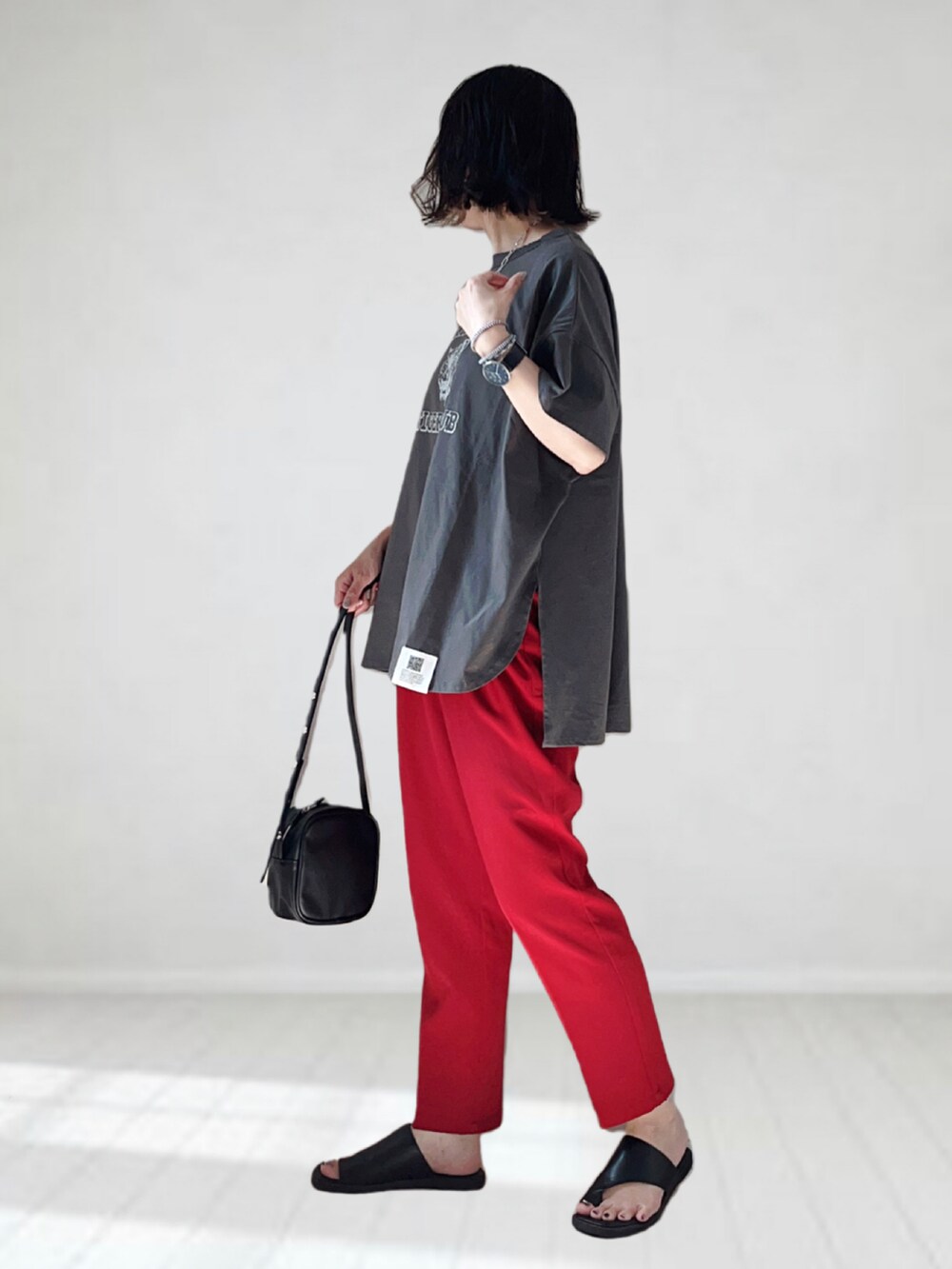 グレー系のTシャツ/カットソー、レッド系のスラックス、ブラック系のショルダーバッグを着用したレディースの夏コーディネートの2枚目の写真