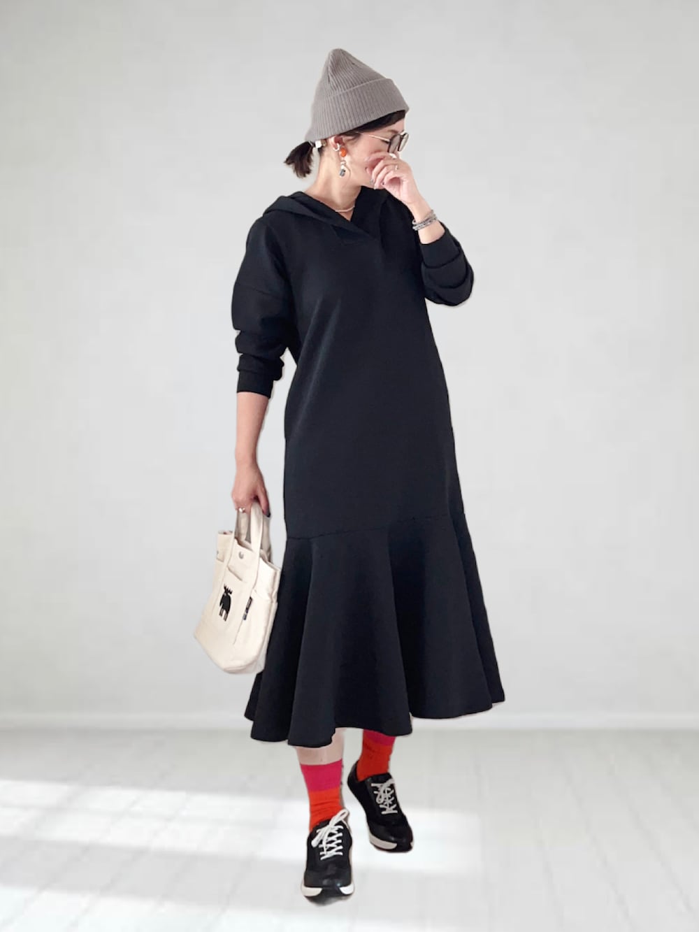 ブラック系のワンピース、ホワイト系のトートバッグ、ブラック系のスニーカーを着用したレディースの夏コーディネートの3枚目の写真